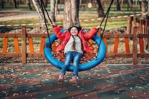 fille enfant heureuse sur la balançoire. petit enfant jouant dans le pack d'automne. photo