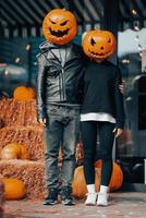 un gars et une fille avec des têtes de citrouille posant dans la rue photo