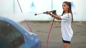 jeune femme lavant une voiture bleue au lave-auto photo