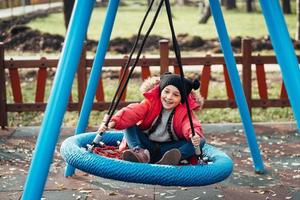 fille enfant heureuse sur la balançoire. petit enfant jouant dans le pack d'automne. photo