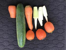 épices de cuisine qui portent le nom de fruits mais qui sont utilisées comme légumes, à savoir carottes, tomates, concombres et maïs sur fond sombre photo