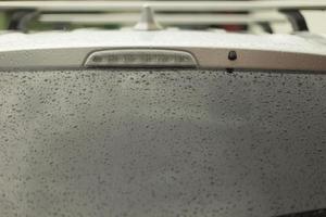 gouttes de pluie sur la fenêtre de la voiture. lunette arrière humide. transport par mauvais temps. photo