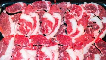 faites glisser du boeuf cru pour yakiniku. mince morceau de boeuf pour shabu hotpot style de cuisine japonaise. gros plan sur un œil de mandrin de viande fraîche pour sukiyaki. vue de dessus photo