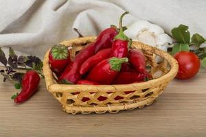 piments rouges dans un panier sur fond de bois photo