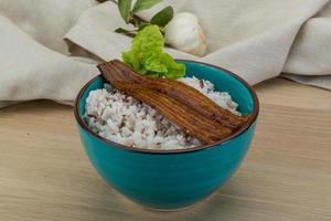 Anguille avec du riz dans un bol sur fond de bois photo