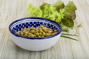 pois marinés dans un bol sur fond de bois photo