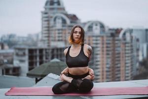 femme pratiquant le yoga sur le tapis sur le toit et faisant des exercices de yoga photo