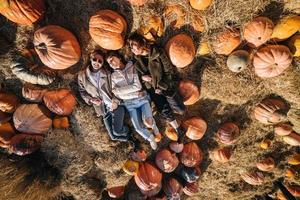 les jeunes filles sont allongées sur des meules de foin parmi les citrouilles. vue d'en-haut photo