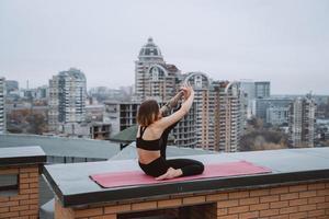 femme pratiquant le yoga sur le tapis sur le toit et faisant des exercices de yoga photo