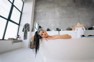 femme détendue prenant un bain, s'amusant et se relaxant allongée dans la baignoire photo