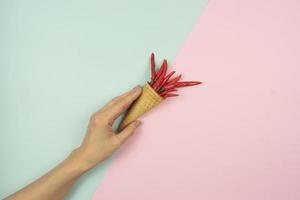 une main de femme tient un cornet gaufré avec des piments rouges dedans photo