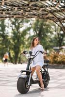 belle jeune femme et un scooter électrique, transport écologique photo