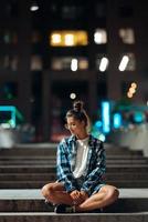 femme assise sur de longues marches de pierre dans la ville nocturne photo