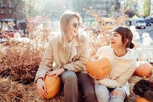 les filles tiennent des citrouilles dans les mains sur le fond de la rue. photo