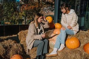 les filles s'amusent parmi les citrouilles et les meules de foin dans une rue de la ville photo