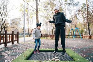 maman et sa fille sautant ensemble sur un trampoline dans le parc d'automne photo