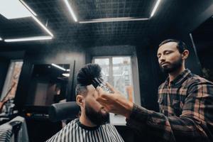 le maître enlève les cheveux restants du client avec une brosse photo