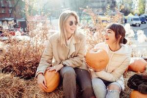 les filles tiennent des citrouilles dans les mains sur le fond de la rue. photo