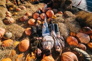 les jeunes filles sont allongées sur des meules de foin parmi les citrouilles. vue d'en-haut photo