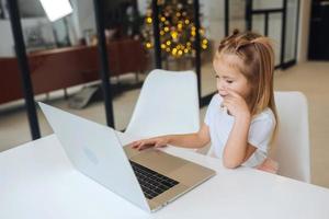 petite fille à l'aide d'un ordinateur tablette assis à table photo