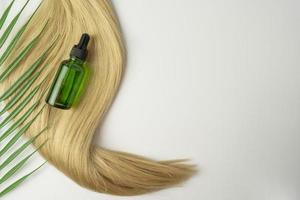 une huile ou un sérum naturel pour le soin des cheveux posé sur une nappe de cheveux blonds photo