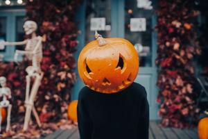 fille avec une tête de citrouille fait peur à la caméra photo