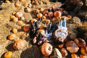 les jeunes filles sont allongées sur des meules de foin parmi les citrouilles. vue d'en-haut photo