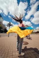 jeune femme porte le drapeau de l'ukraine flottant derrière elle photo