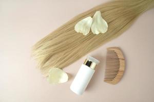 une mèche de cheveux blonds, un flacon compte-gouttes d'huile essentielle naturelle pour le traitement des cheveux photo