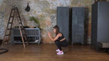 une jeune fille athlétique effectue un squat avec un dos plat et les bras croisés devant elle photo