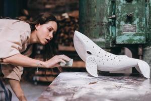portrait de jeune femme travaille soigneusement sur une baleine en céramique en atelier. photo