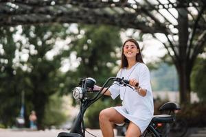 belle jeune femme et un scooter électrique, transport écologique photo