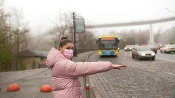 jeune femme debout sur la route à l'extérieur levant la main de côté attraper un taxi photo