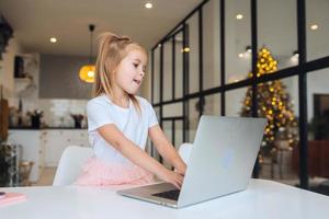 petite fille à l'aide d'un ordinateur tablette assis à table photo