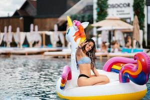 femme sur matelas gonflable licorne flotteur dans la piscine. photo