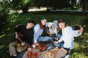 compagnie de beaux jeunes et chien prenant un déjeuner en plein air. photo