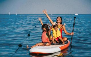 mère avec deux filles debout sur un paddle board photo