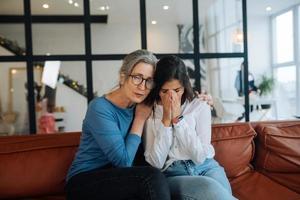 grand-mère réconfortant sa petite-fille triste à la maison. photo