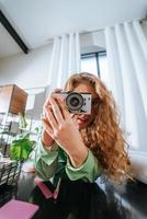 Cheerful young woman making photo sur appareil photo à la maison