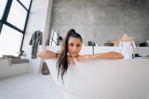 femme détendue prenant un bain, s'amusant et se relaxant allongée dans la baignoire photo