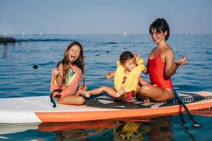 maman et deux petites filles faisant du yoga sur le paddle board photo