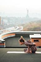 femme faisant du yoga sur le toit d'un gratte-ciel dans une grande ville. photo