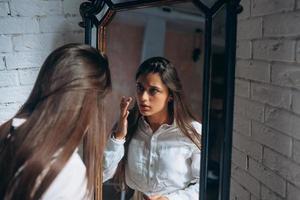 jeune femme regarde attentivement dans le miroir. photo