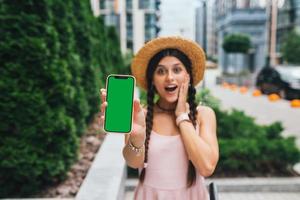 femme montrant un smartphone moderne avec écran vert pour le remplacement photo