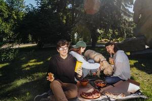 compagnie de beaux jeunes et chien prenant un déjeuner en plein air. photo