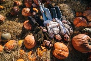 les jeunes filles sont allongées sur des meules de foin parmi les citrouilles. vue d'en-haut photo