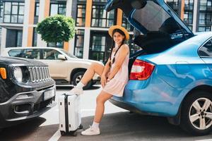 femme emballant sa valise dans le coffre à bagages de la voiture. photo