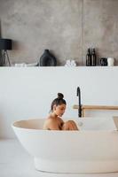 vue latérale d'une femme prenant un bain moussant à la maison photo