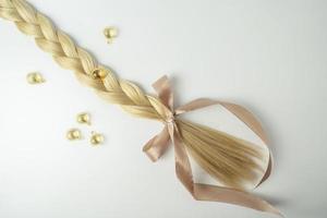 cheveux blonds naturels et huile essentielle pour le traitement des cheveux dans des capsules dorées sur fond blanc photo