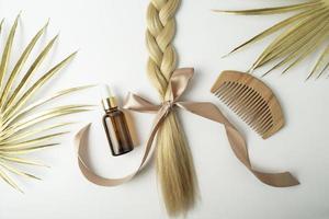 cheveux blonds naturels et huile essentielle pour le traitement des cheveux allongé sur un fond blanc photo